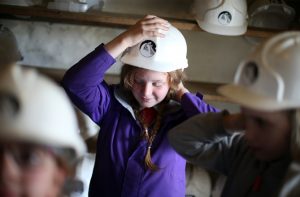 Young school girl putting her Killhope mining helmet on