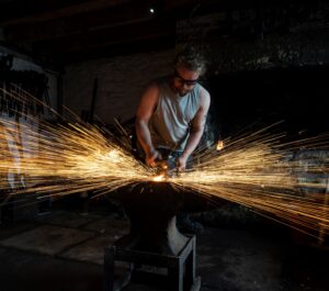 Blacksmith at forge with sparks coming off the metal